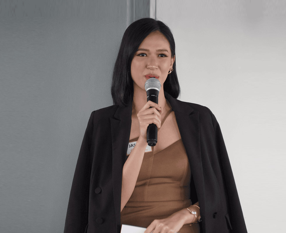 A woman dressed in brown holds a microphone, poised and ready to engage her audience with her voice.